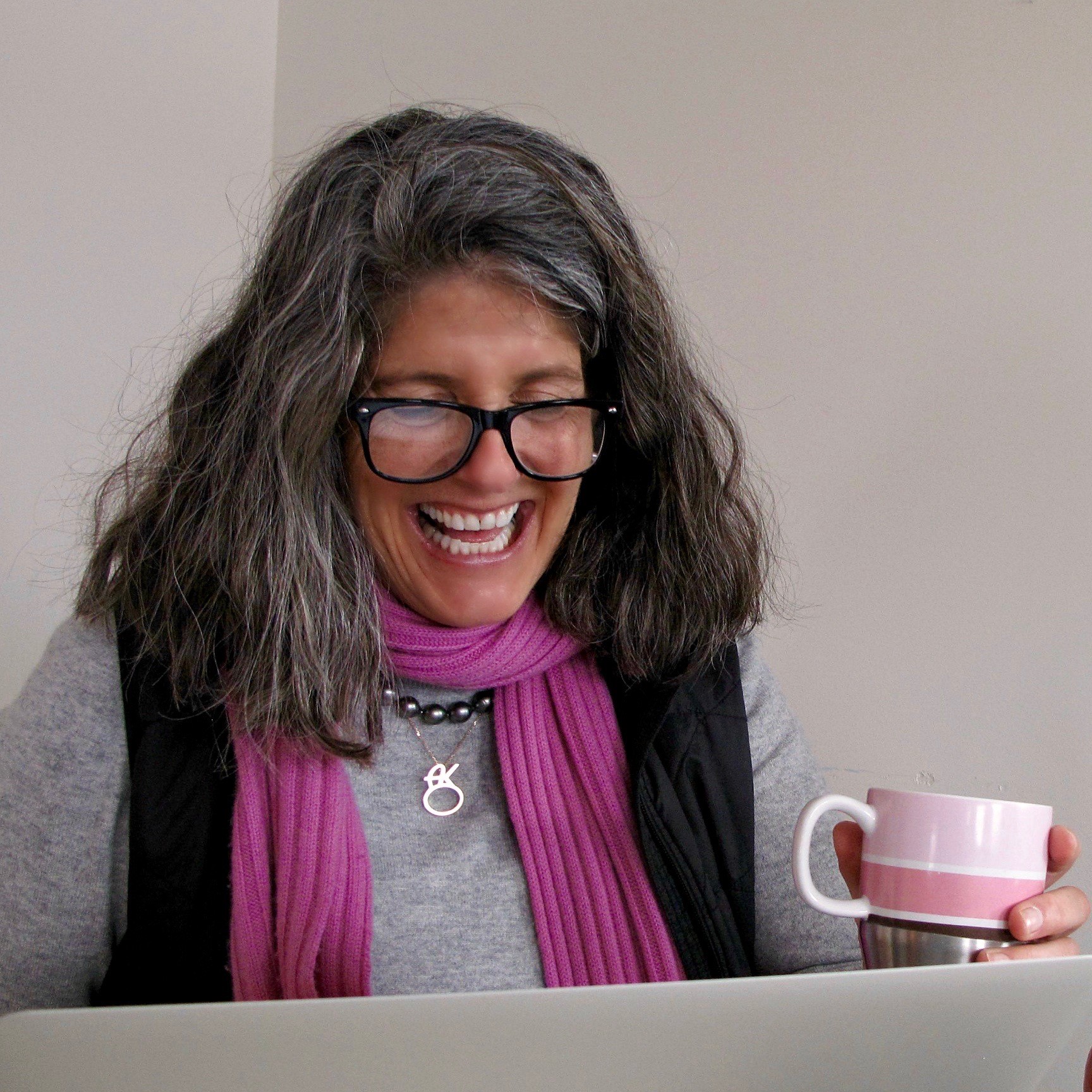Amy Kellogg laughs while holding a pink mug